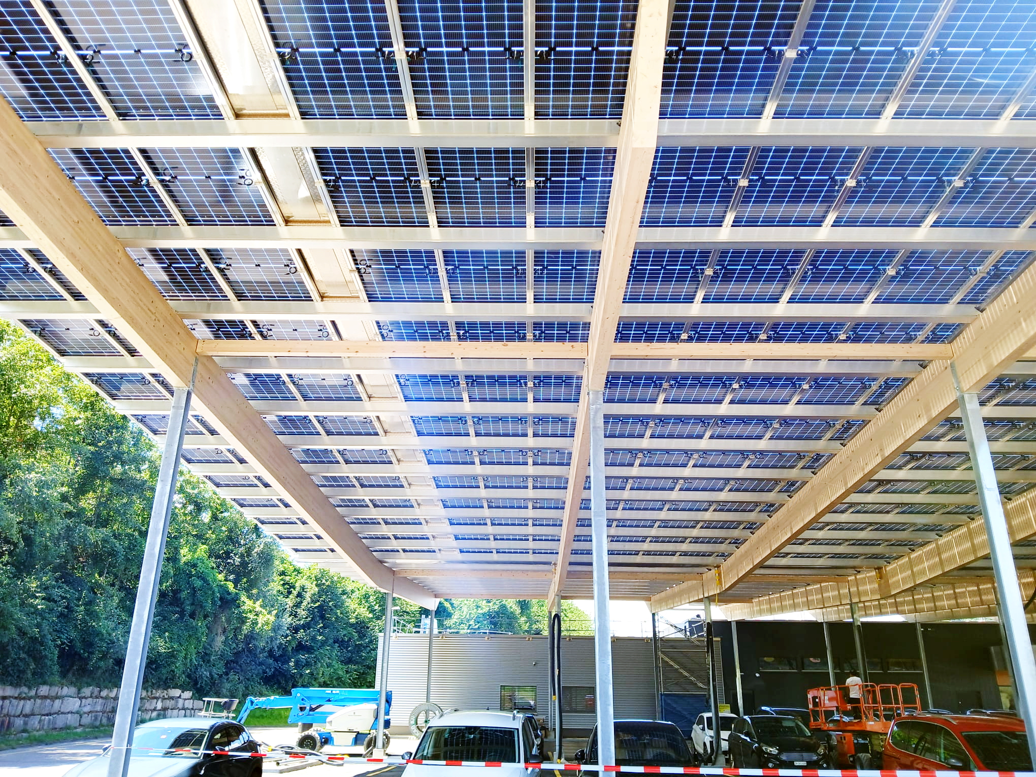 ClickCon Solarpark Migros Pfungen – Luftaufnahme des großen Solarcarports mit hunderten Solarmodulen auf dem Parkplatz des Migros Marktes in Pfungen, Schweiz﻿