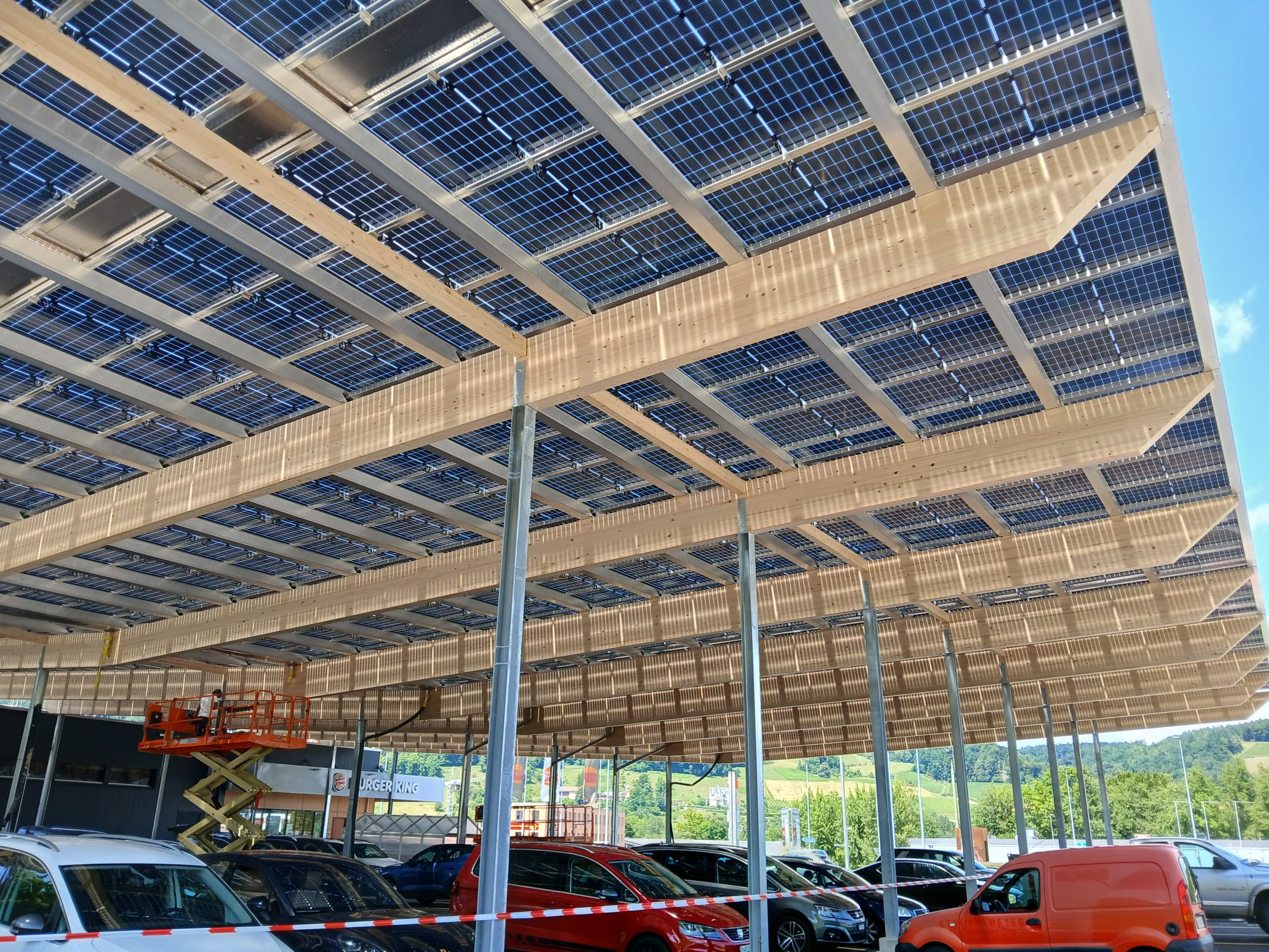 ClickCon Solarcarport Pfungen – Detailansicht der Photovoltaikmodule und Holzträger, nachhaltige Parkplatzüberdachung für Migros Projekt Schweiz﻿