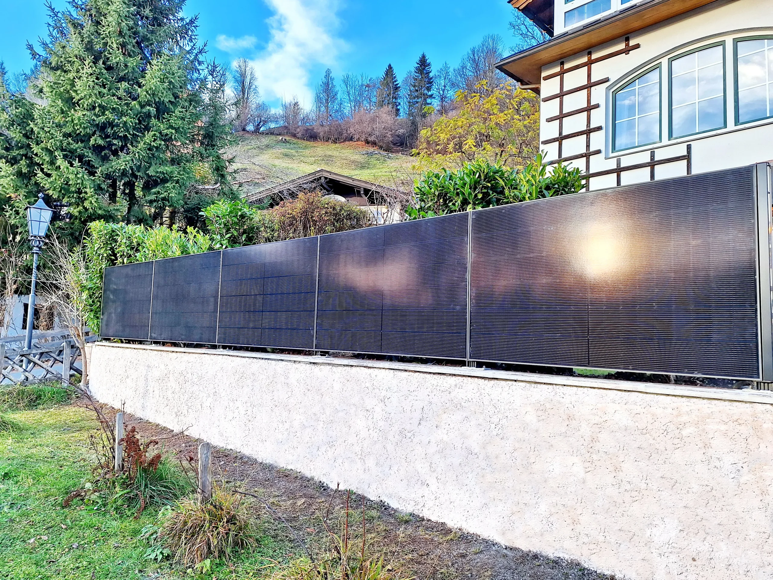 Solarzaun ClickWall von ClickCon als eleganter Sichtschutz vor einem Wohnhaus mit Garten.