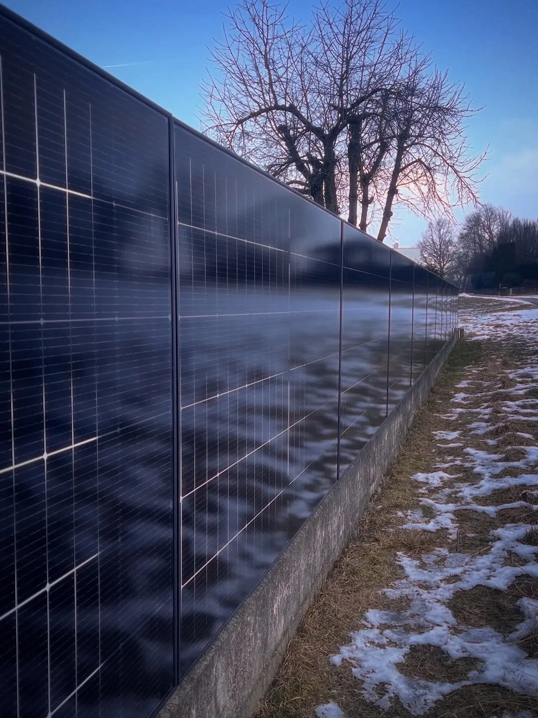 Solarzaun ClickWall von ClickCon entlang einer Grundstücksgrenze mit verschneiter Landschaft im Hintergrund.